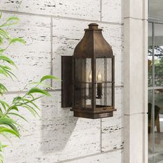 an outdoor wall light on the side of a white brick building next to a potted plant