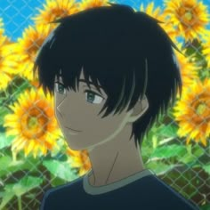 a young man standing in front of a fence with sunflowers on the background