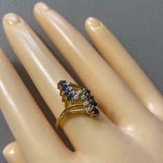 a woman's hand with a ring on it that has three blue and white stones