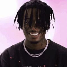 a young man with dreadlocks and a black shirt is smiling at the camera