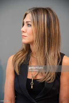 an image of a woman with long hair wearing a black dress and gold chain necklace