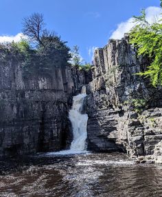 a large waterfall is coming out of the side of a cliff