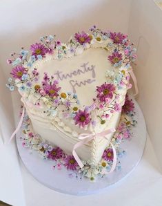 a heart shaped cake decorated with flowers and the words twenty nine written on it in white frosting