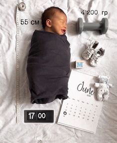 a baby is sleeping next to a calendar