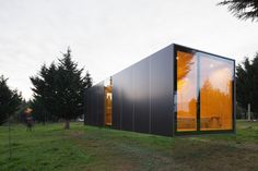 a small black building sitting on top of a lush green field next to tall trees