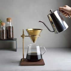 a person pours coffee into a glass cup