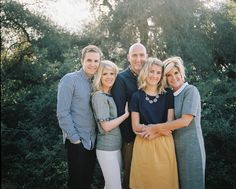 a group of people standing next to each other in front of some bushes and trees