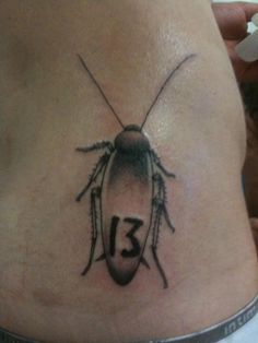 a woman's stomach with a tattoo of a bug on the side and number thirteen