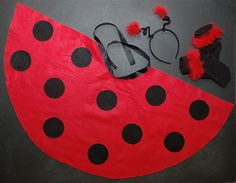 a ladybug costume is laying on the floor next to some shoes and sunglasses