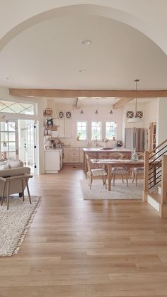 a large open living room and dining area with hardwood floors, white walls and ceiling