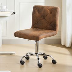 a brown office chair sitting on top of a hard wood floor next to a window