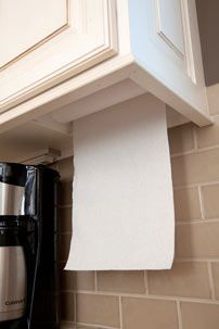 a roll of toilet paper is hanging on the wall above a black coffee pot and microwave