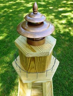 a wooden tower with a metal top sitting in the grass