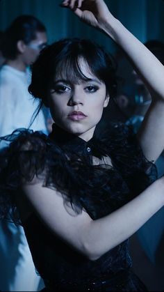 a woman in a black dress with feathers on her shoulders and arms behind her head