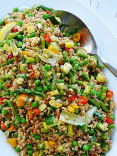 a white plate topped with rice and veggies next to a silver serving spoon