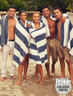 a group of people standing next to each other under a blue and white striped towel