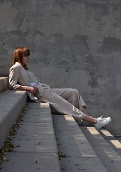 a woman with red hair sitting on concrete steps