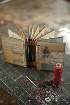 an open book sitting on top of a table next to a spool of thread