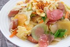 a white plate topped with lots of food on top of a gray tablecloth covered table