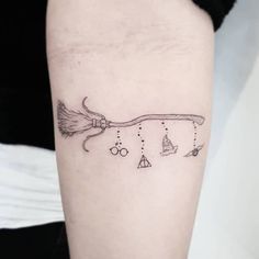 a black and white photo of a broom tattoo on the right arm, with other items around it