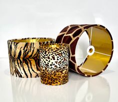 three different animal print candle holders on a white surface with a clock in the middle