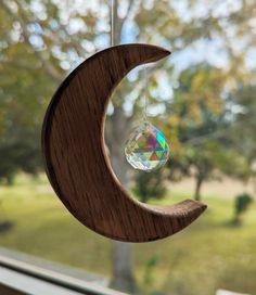 a wooden crescent with a crystal ball hanging from it's side on a window sill