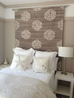 a bed with white pillows and decorative wallpaper on the headboard in a bedroom