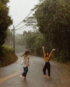 two people jumping in the rain on a road