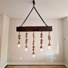 a chandelier made out of rope and bulbs hanging from it's ceiling