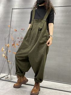 a person standing in front of a wall wearing overalls