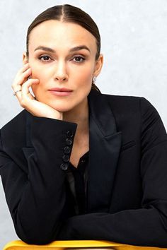 a woman sitting at a yellow suitcase with her hand on her chin and looking off to the side