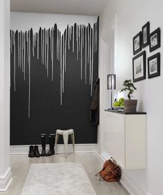 a hallway with black and white paint dripping on the wall, two stools next to it