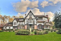 a large house with lots of windows in the middle of a grassy area next to trees and bushes