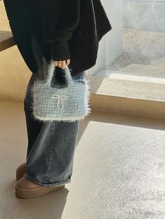 a woman is holding a handbag in her right hand while standing on the ground