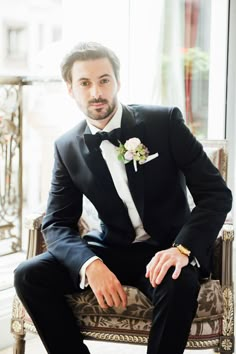 a man in a tuxedo sitting on a chair