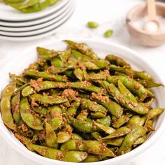 a white bowl filled with green beans on top of a table