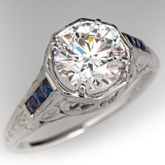 an antique style diamond ring with blue sapphires on the sides and white gold accents