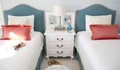 two white beds with red pillows and blue headboards