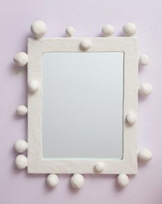 a mirror that has some balls on the top of it and is hanging up against a wall