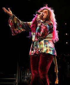 a woman with pink hair singing into a microphone