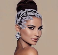 a woman wearing a silver headpiece with leaves on it's forehead and earrings