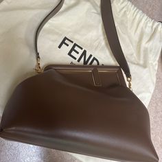 Fendi First Bag In The Perfect Size For Daytime, Made Of Soft, Brown -Color Nappa Leather, With Oversized Metal F Clasp Bound In Tone On Tone Nappa Leather. Featuring An Interior Compartment Lined In Fabric With The Iconic Ff Motif, Removable Inner Hooks And Gold-Finish Metalware. Can Be Carried By Hand As A Clutch Or Worn On The Shoulder Or Cross-Body Thanks To The Detachable Shoulder Strap. Made In Italy Measurements Height : 20 Cm Depth : 14 Cm Width : 30 Cm Weight : 0.96 Kg Fendi First Bag, Fendi First, Brown Leather Bag, Tone On Tone, Soft Brown, One Bag, Fendi Bags, Nappa Leather, Gold Finish