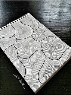 a black and white spiral notebook sitting on top of a wooden table