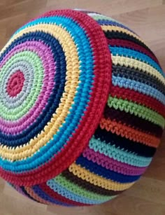 multicolored crocheted round floor cushion on wooden floor next to wood floor