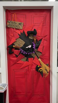 a red door decorated with halloween decorations and witch's hat, broom, and sign