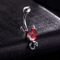 a red heart shaped navel ring sitting on top of a black surface