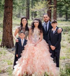 a family posing for a photo in the woods wearing formal clothes and tuxedos