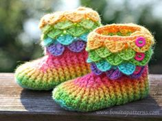 there is a pair of crocheted baby booties with buttons on the front