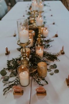 a long table with candles and greenery on it