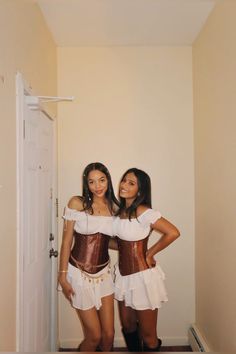 two women dressed in corsets standing next to each other near an open door